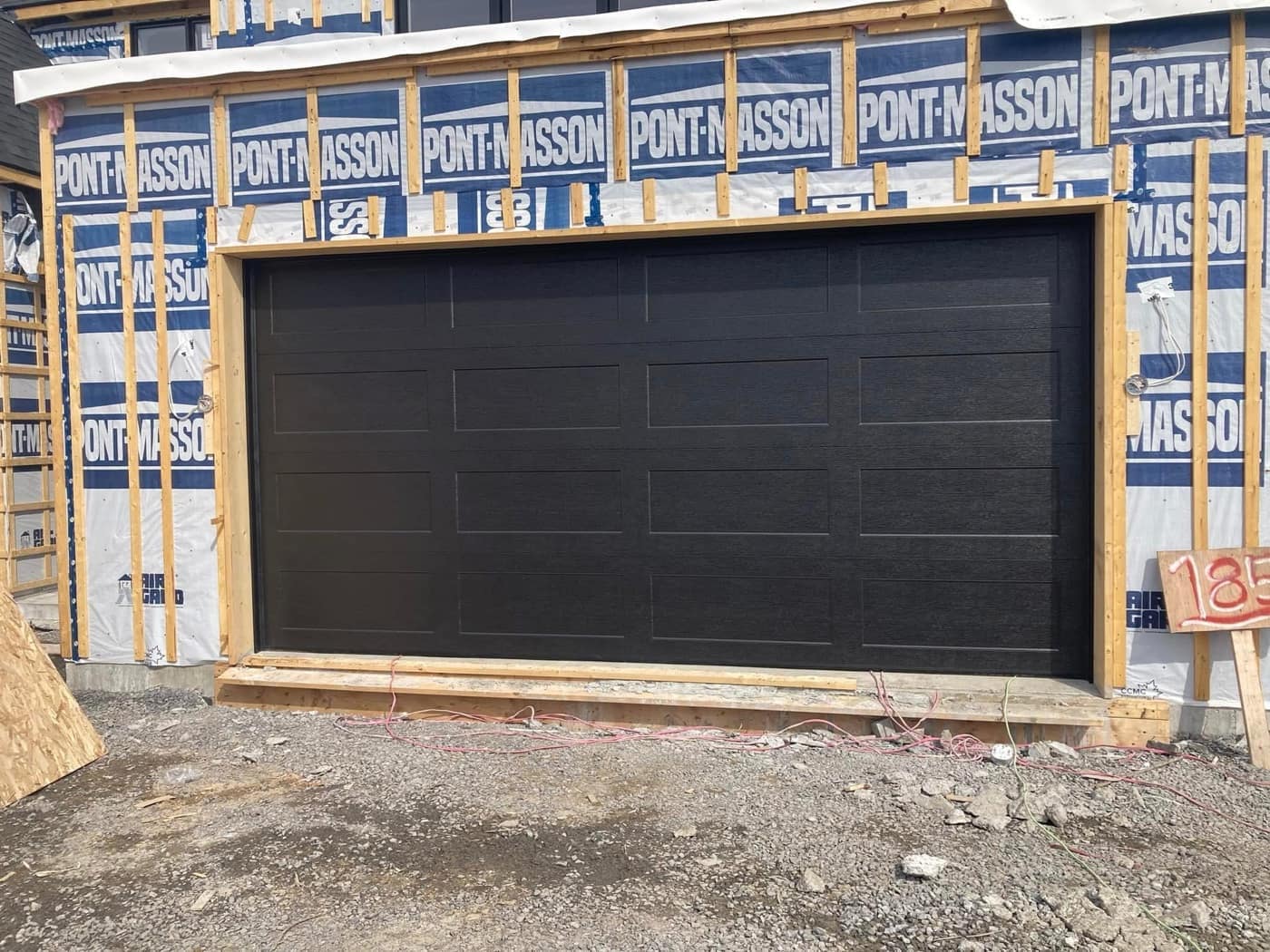Porte de garage noire posée sur une construction neuve