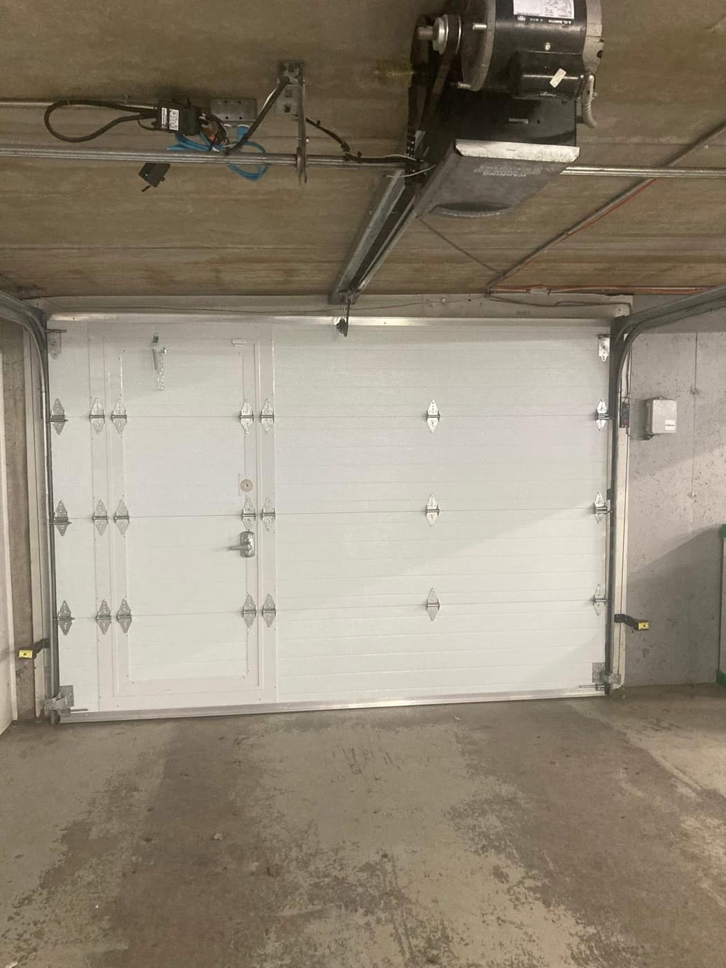 Porte de garage blanche avec son ouvre-porte au plafond