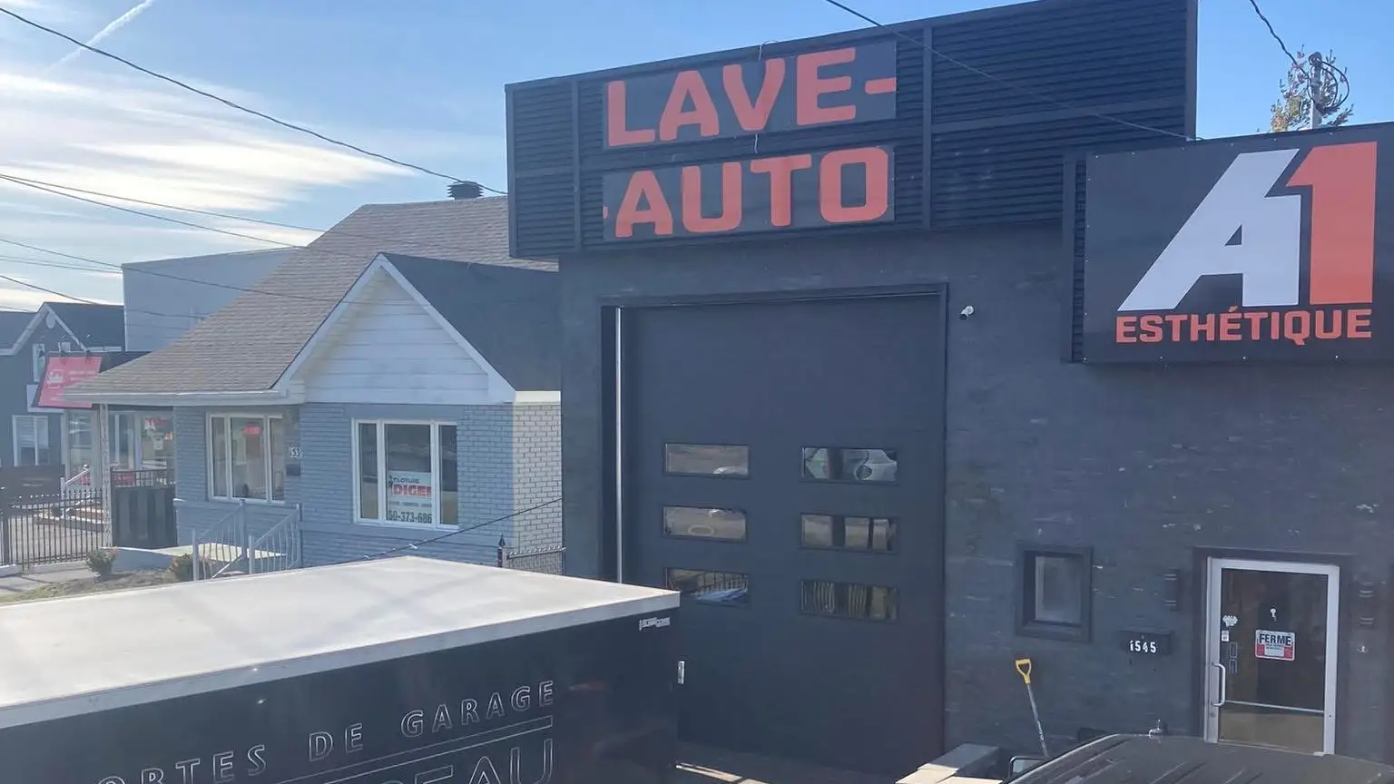 Porte de garage commerciale noire d'un lave-auto, la remorque de Portes de garage Trudeau devant